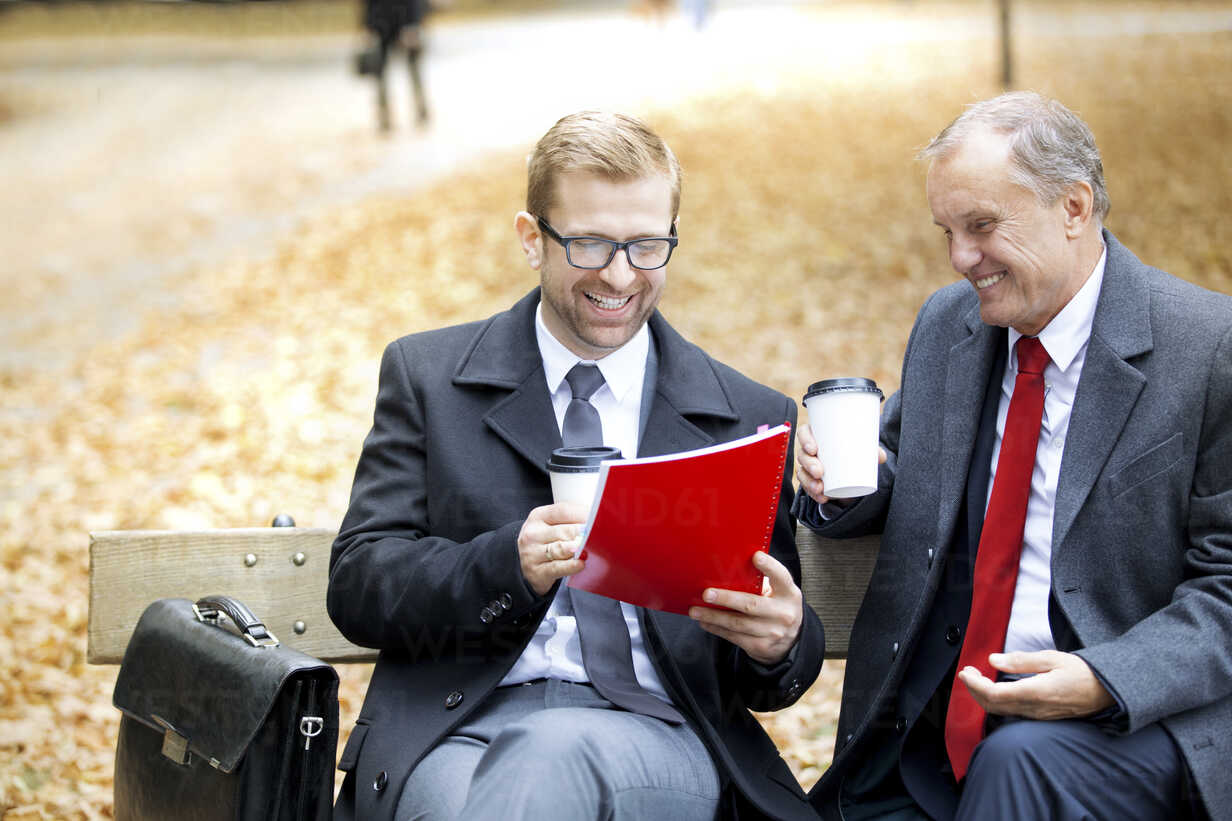 Two Happy Businessmen With Document And Coffee To Go On Park Bench Westf Fotoagentur Westend61 Westend61