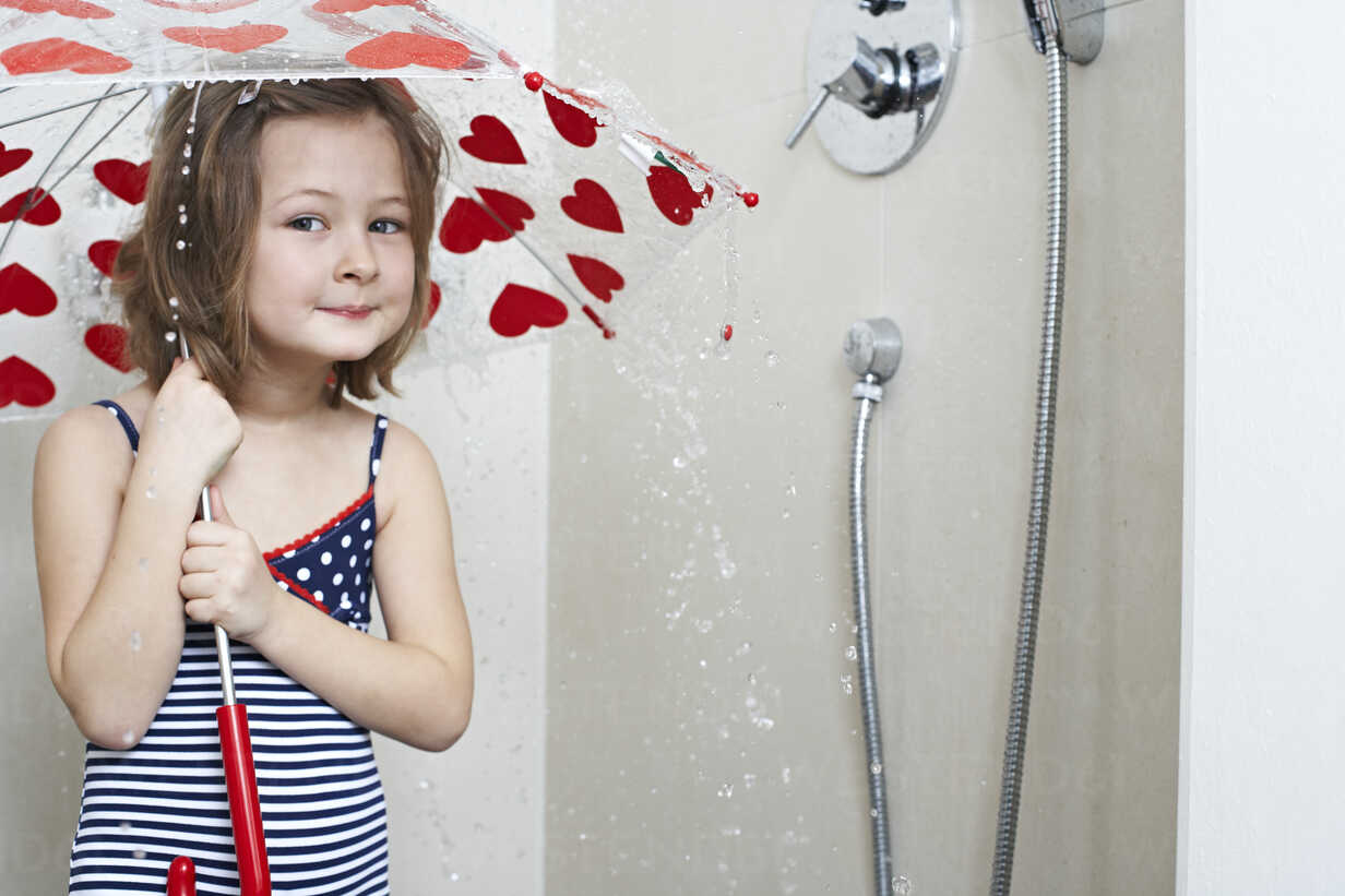 Portrait Of Smiling Little Girl Taking Shower With Umbrella FSF00851