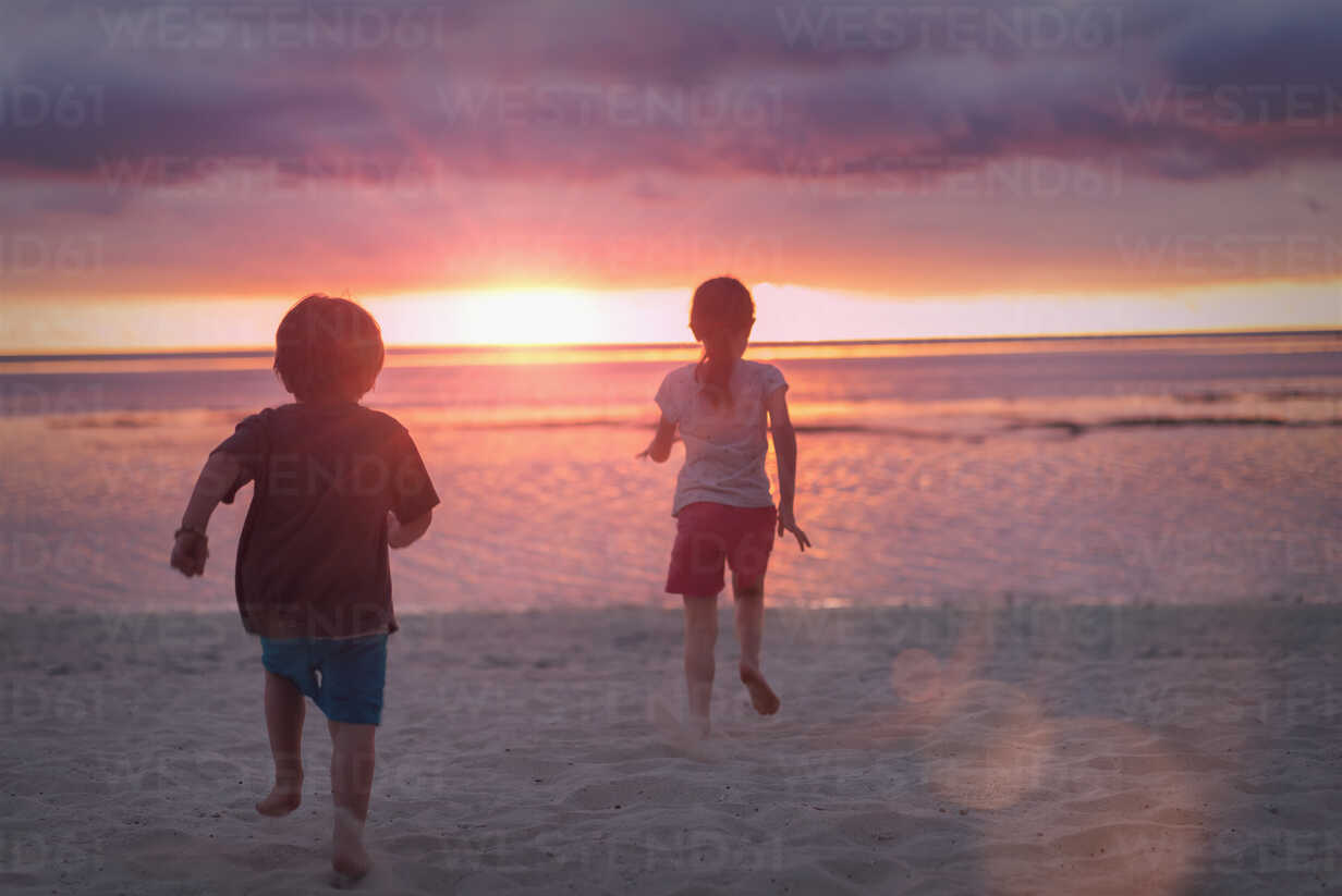 Boy And Girl Brother And Sister On Tranquil Sunset Beach With Dramatic Sky Stockphoto