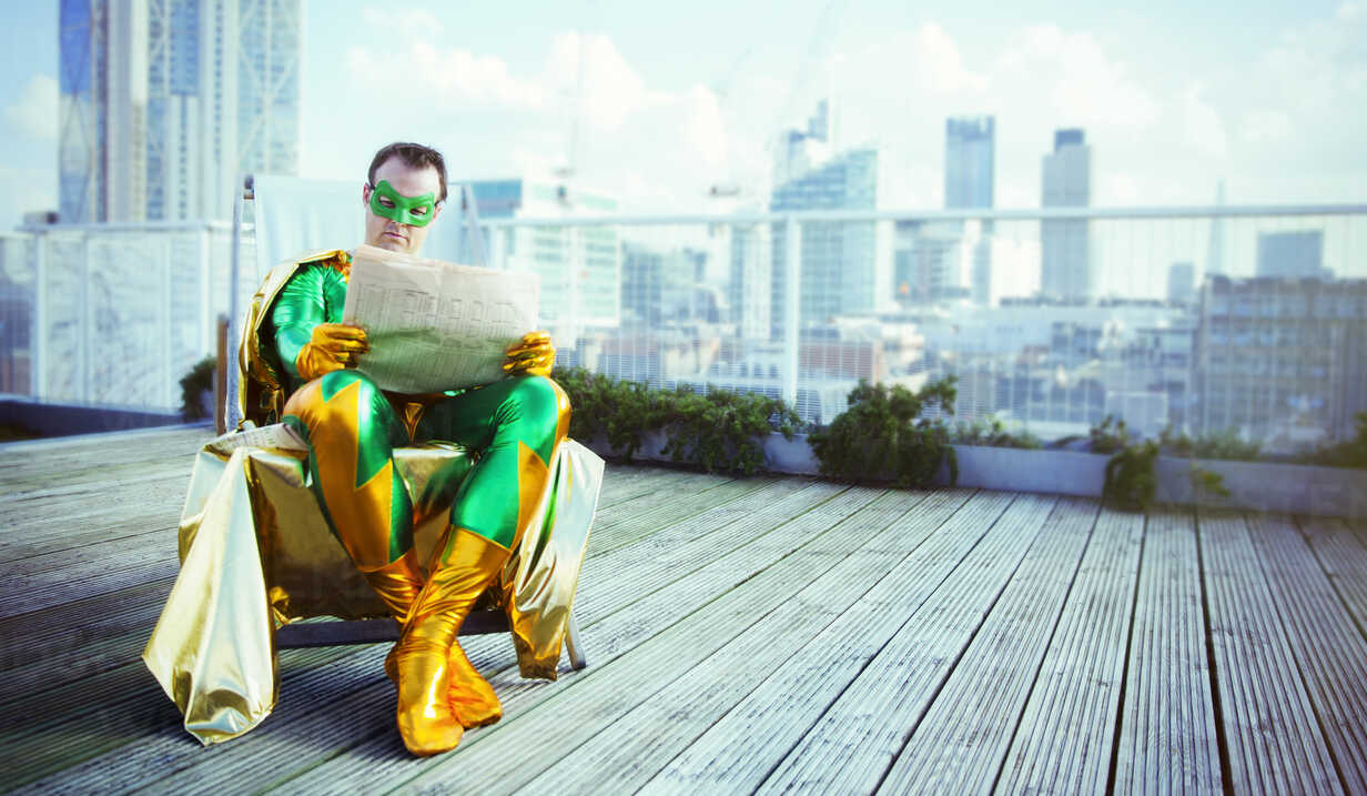 Superhero Reading Newspaper On City Rooftop Stockphoto
