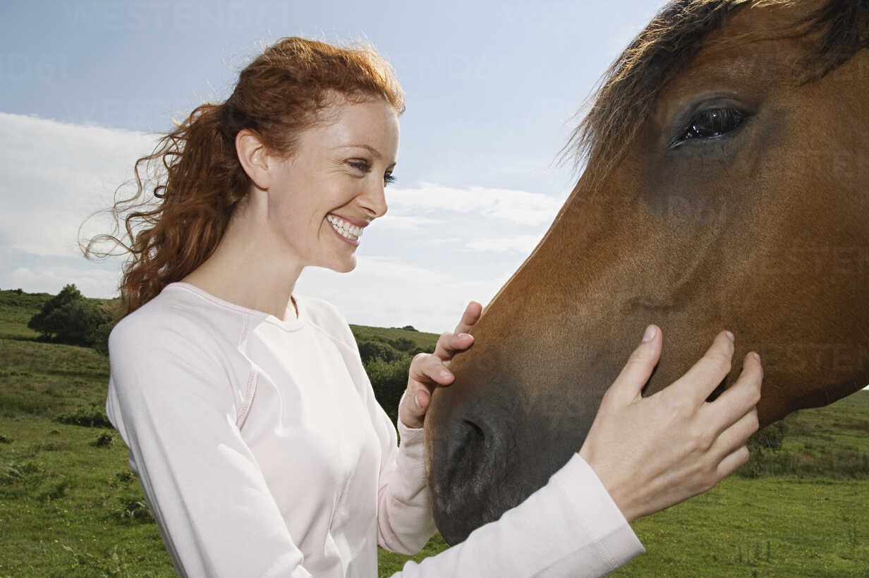 A Young Woman Stroking The Muzzle Of A Bay Horse Minf Mint Images Westend61