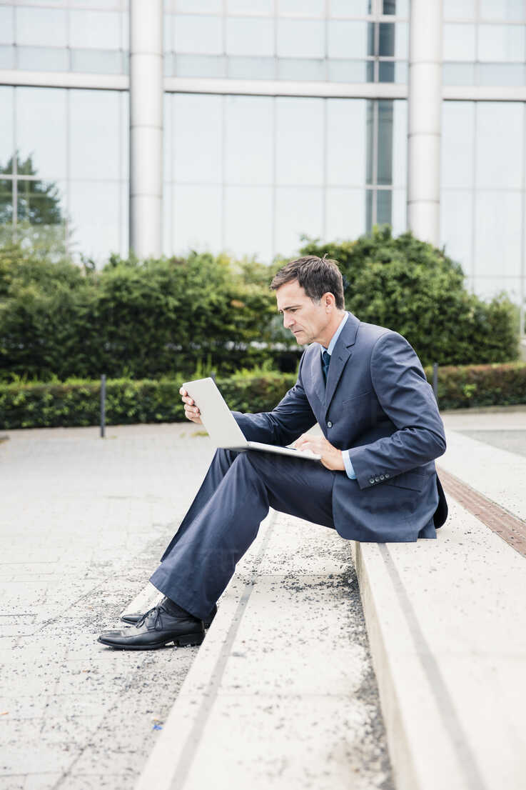 Serious Businessman Sitting Down Using Laptop In The City Moef Robijn Page Westend61