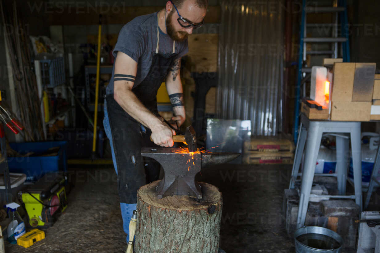 blacksmith-forging-knife-on-anvil-with-hammer-in-workshop-CAVF50414.jpg