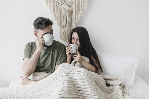 Happy Couple Sitting In Bed Drinking Coffee Having Fun