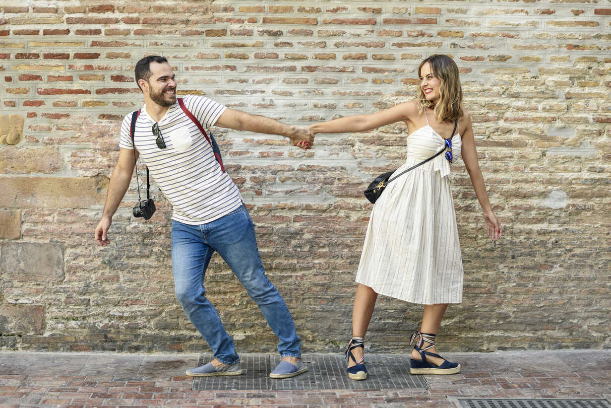 Happy Couple Holding Hands Walking In Opposite Directions At Brick Wall Jsmf Javier Sanchez Mingorance Westend61