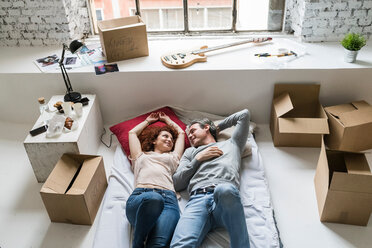 Couple Moving Into Industrial Style Apartment Lying On Mattress Stockphoto