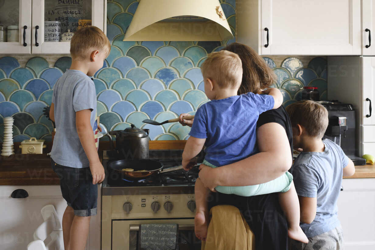 Mother Cooking With Her Three Sons In The Kitchen Stockphoto