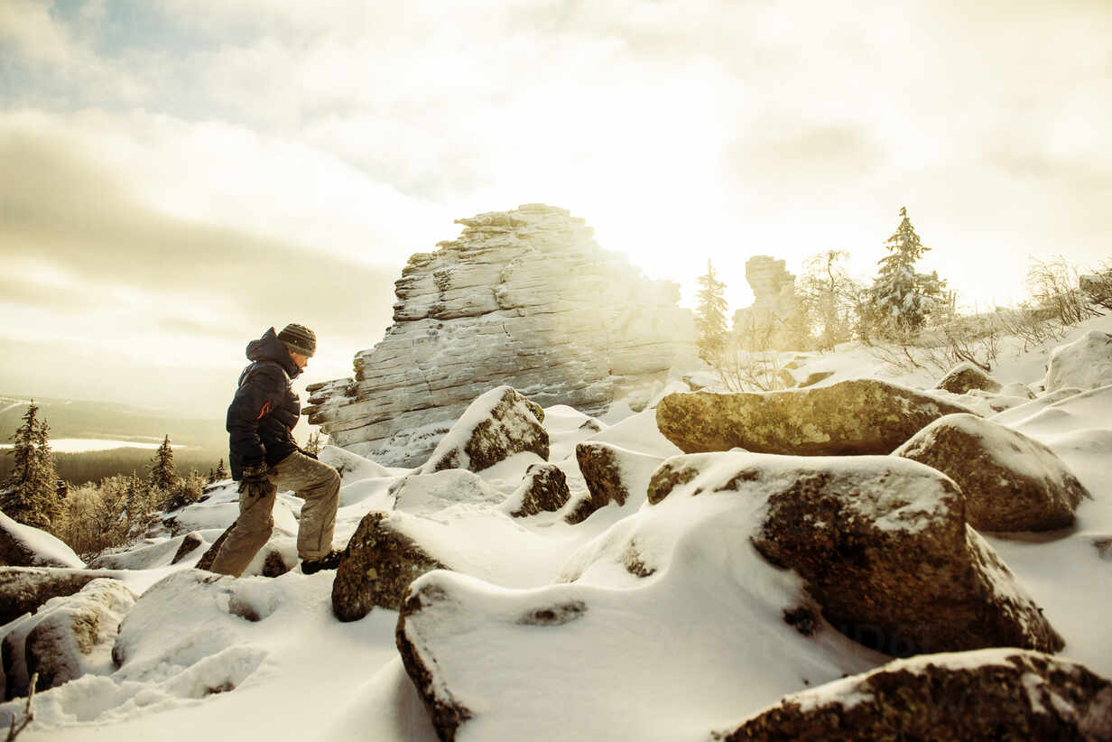 Caucasian Hiker Climbing Snowy Rock Formations Stockphoto