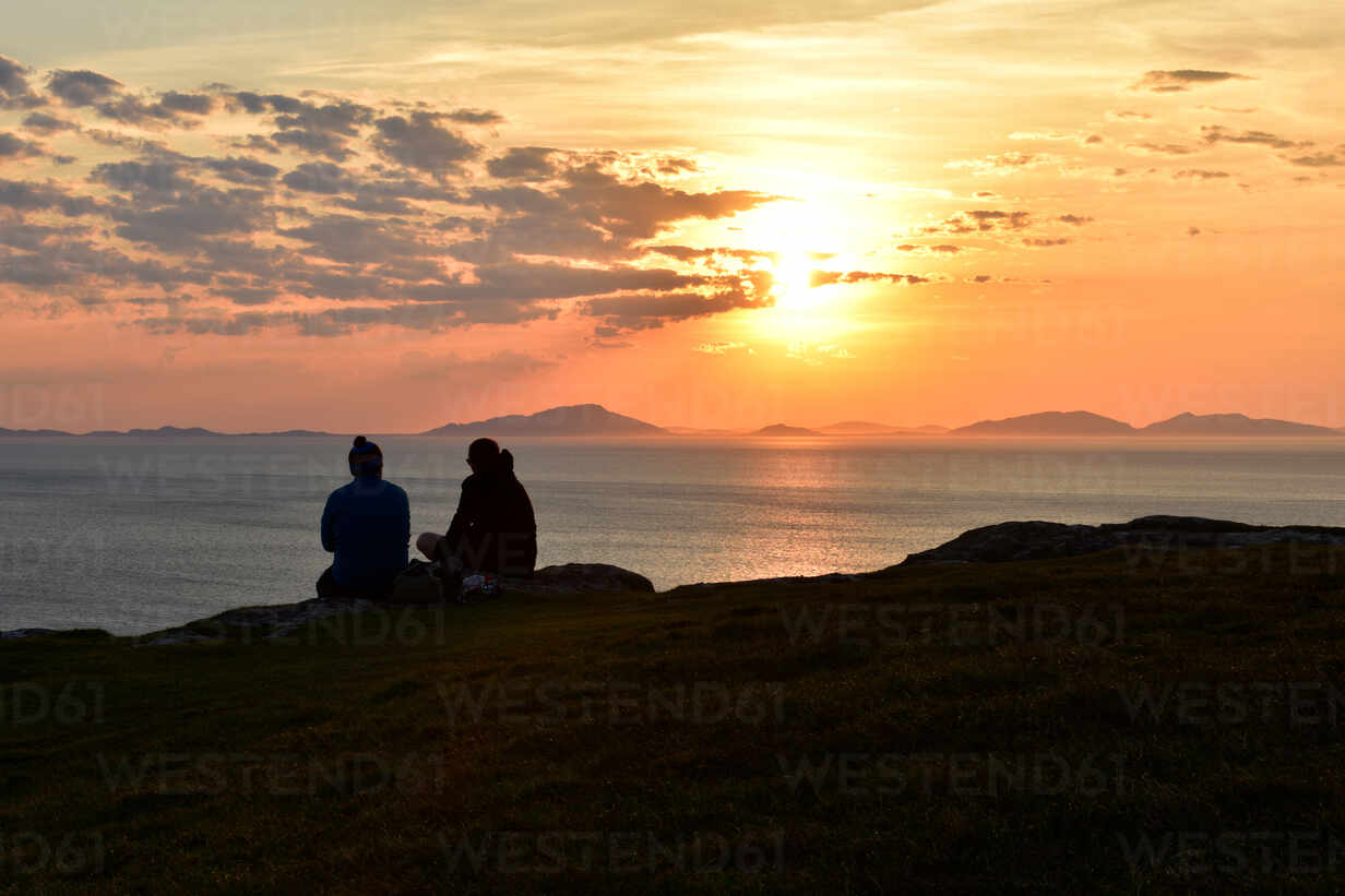 Two Tourists Enjoying A Beautiful Sunset At Neist Point On The Isle Of Skye Inner Hebrides