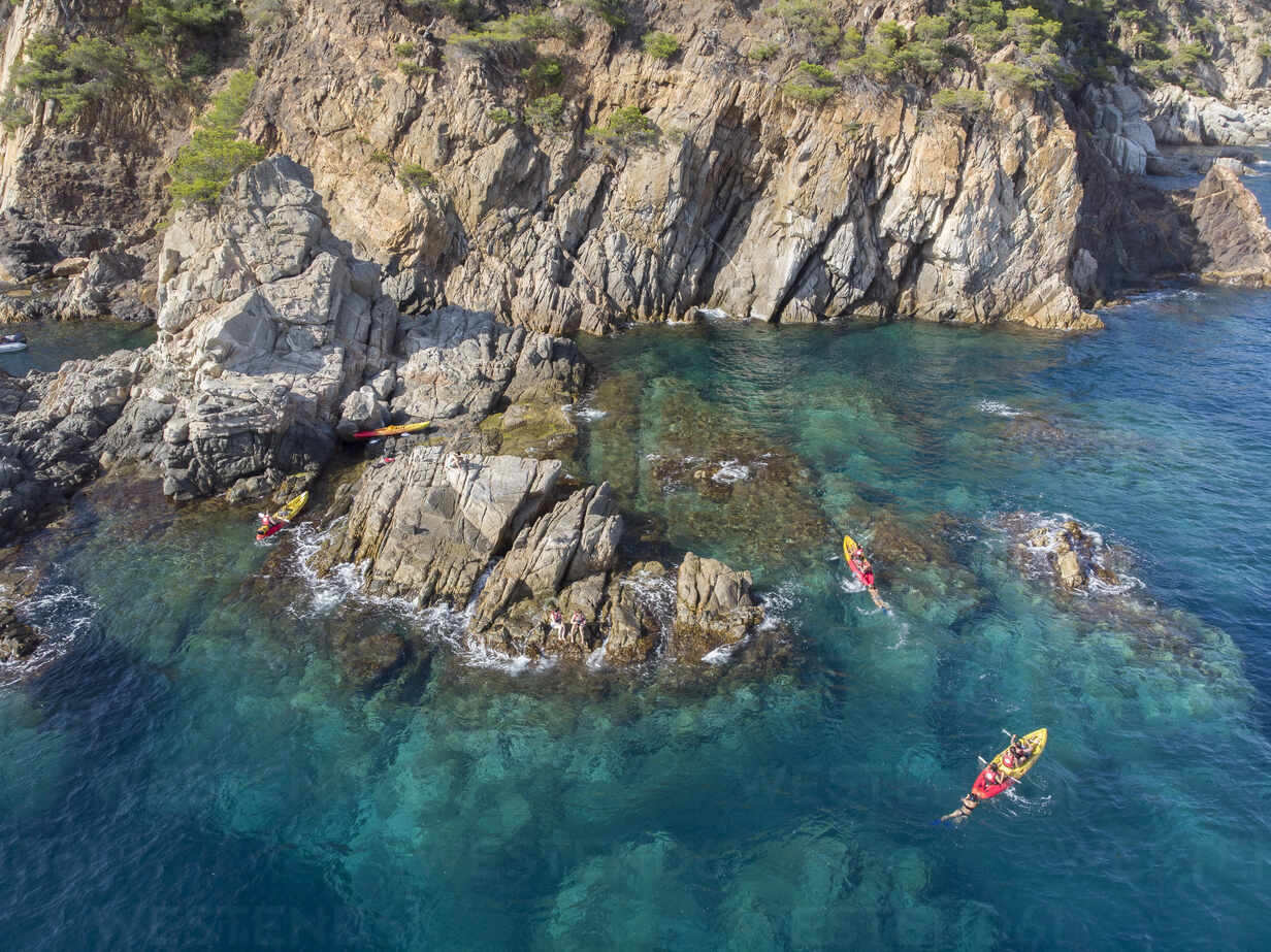 A group of friends playing and kayaking in a Mediterranean cove. –  Stockphoto
