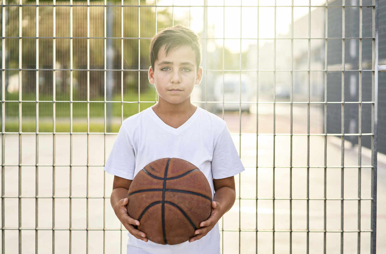 Kid with green eyes playing basketball alone in a street – Stockphoto
