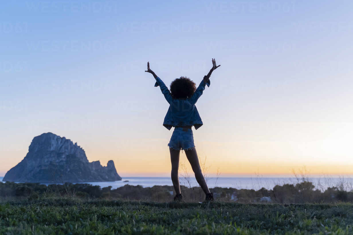 Rear View Of Young Woman Standing On A Viewpoint With Raised Arms At Sunset Ibiza Afvf04404