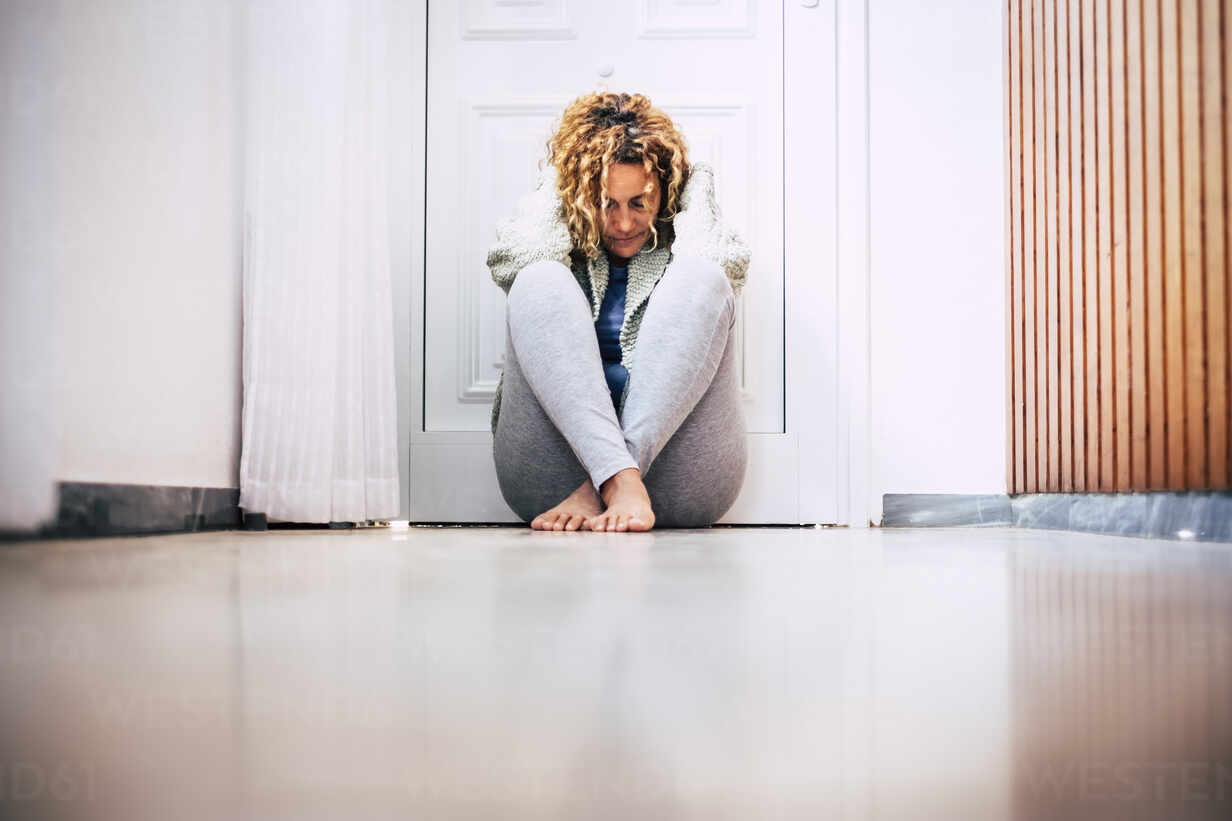 Despaired Woman Sitting On Floor In Corridor In Front Of Locked Door Sipf Simona Pilolla Westend61