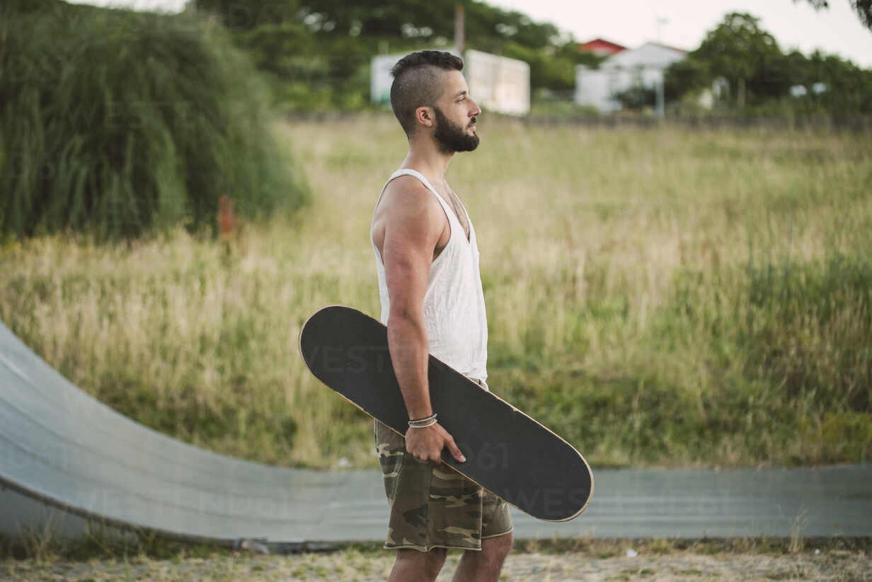 Handsome Young Man Holding Skateboard Looking Away While Standing On Land Raef02388 Ramon