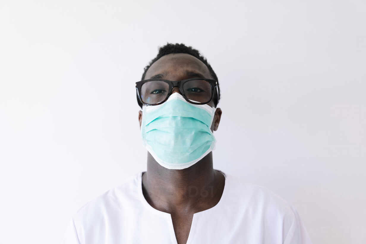 Close-up of afro doctor wearing surgical mask against white background ...