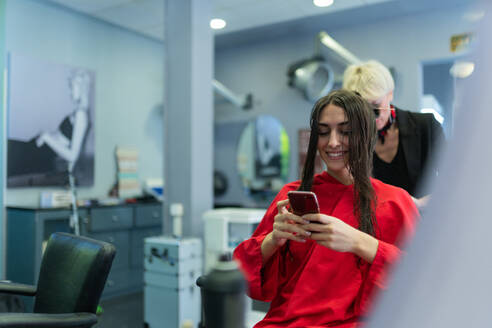 Young Woman With Mobile Phone And Sitting On Chair With Beautiful Hairstyle In Hairdressing Salon Adsf Addictive Stock Creatives Westend61