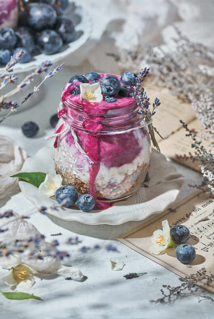 Glass Jar With Nutritious Yogurt With Healthy Granola And Fresh Blueberries Placed On Table For Breakfast
