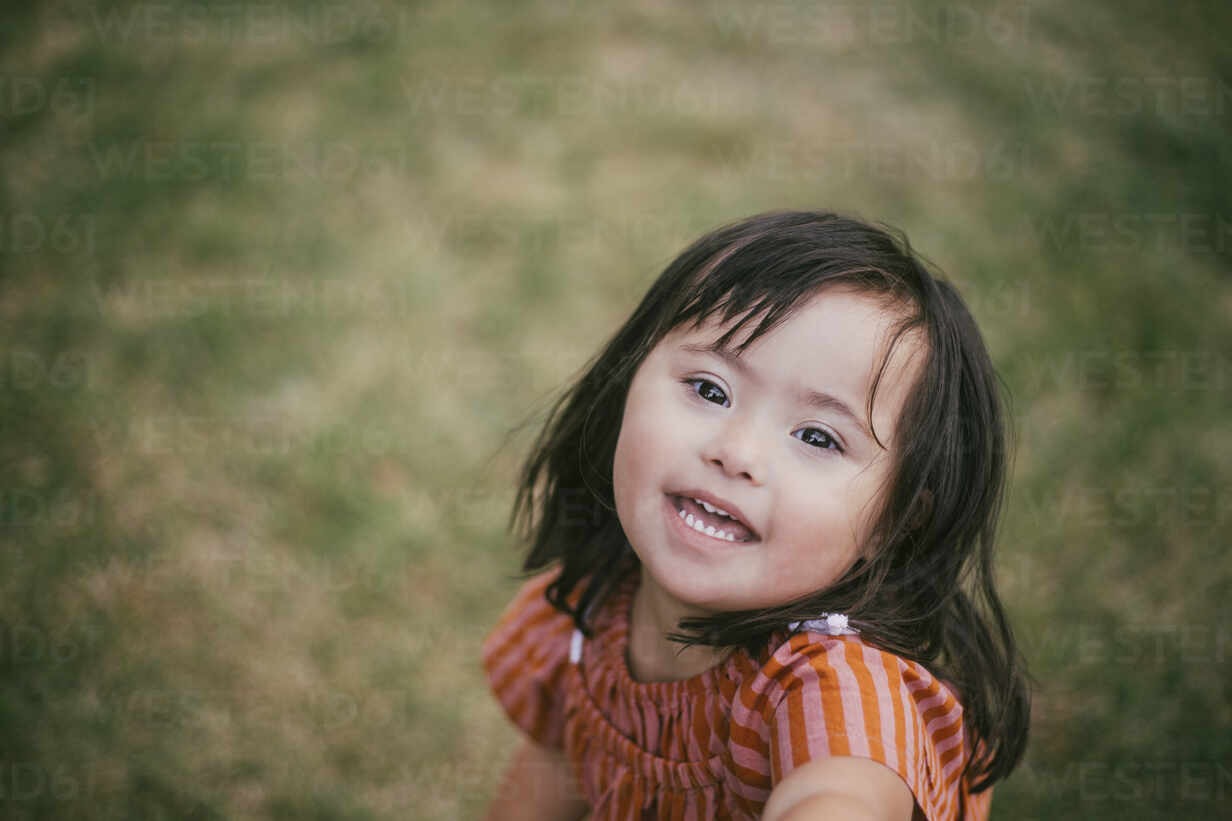 Portrait Of Smiling Down Syndrome Girl Playing In Yard Masf9 Maskot Westend61