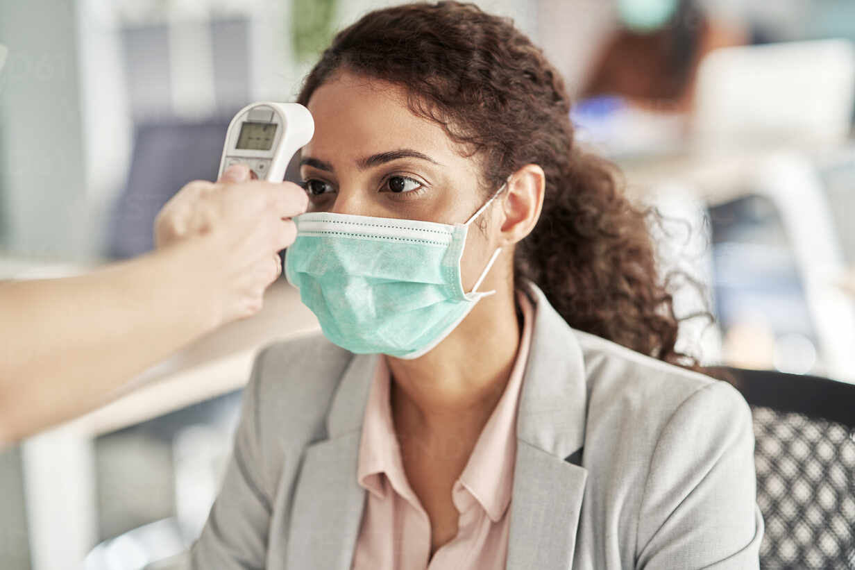 Female Professional Going Through Thermometer Checkpoint At Work Place Stockphoto