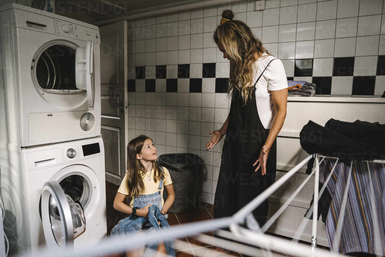 Mother And Daughter Doing Laundry In Utility Room Stockphoto