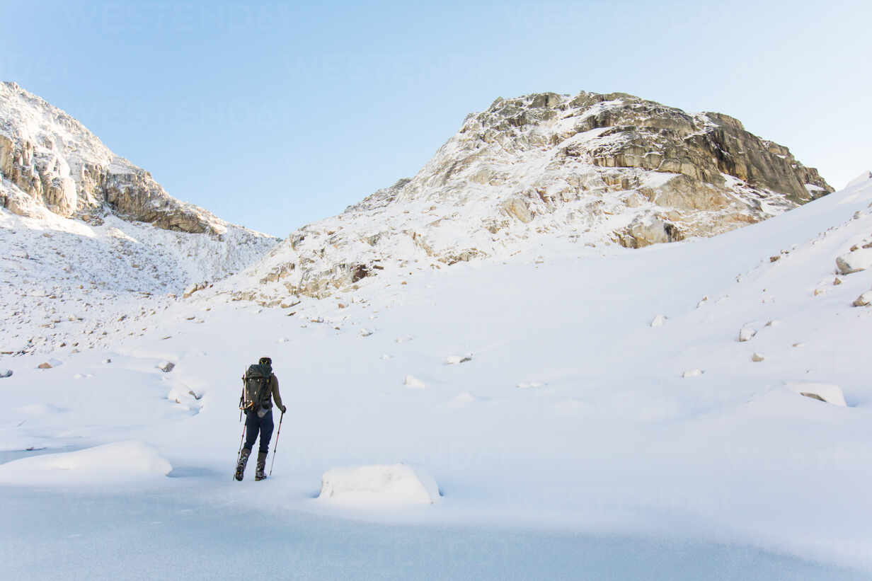 Explorer Traverses Snowy Landscape Towards Rocky Mountain Summit Stockphoto